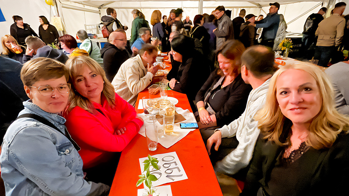 Viele Menschen in einem Festzelt, sie feiern ein Klassentreffen. Im Vordergrund drei Frauen an einem Tisch.