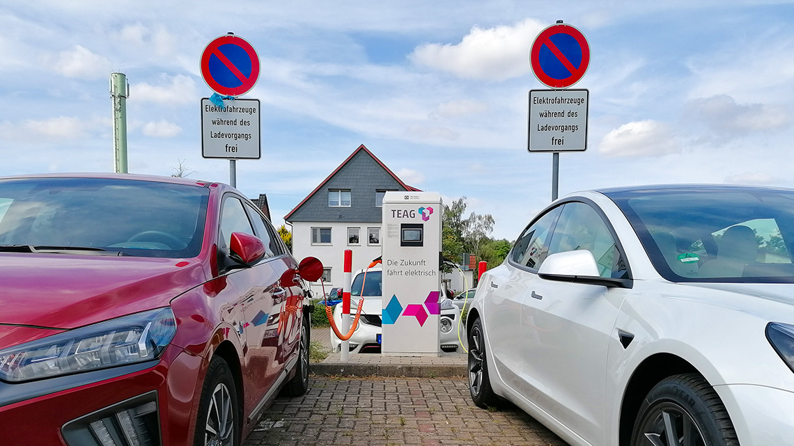Eine Ladestation von der Firma TEAG für elektrische Fahrzeuge, ein roter und ein weißer PKW sind angeschlossen und laden.