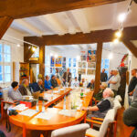 Viele Männer sitzen um einen großen Tisch herum im Heimatmuseum Ilfeld. Sie begehen ein Jubiläum.