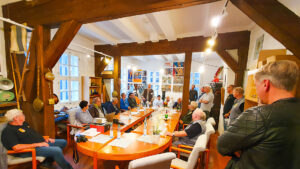 Viele Männer sitzen um einen großen Tisch herum im Heimatmuseum Ilfeld. Sie begehen ein Jubiläum.