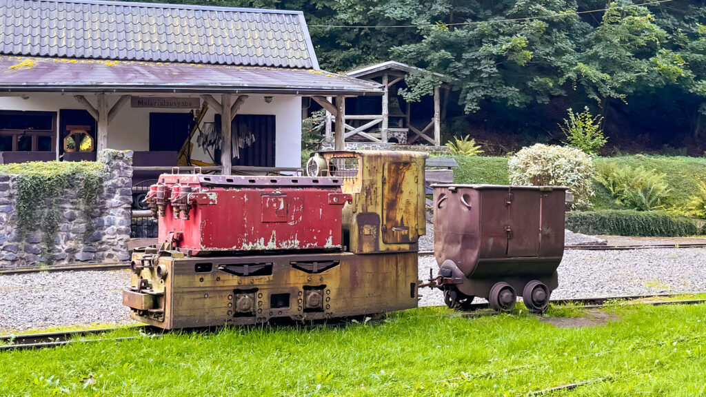 Eine alte Grubenlok steht vor einem Haus, das zum Besucherbergwerk Rabensteiner Stollen gehört.