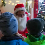 Zwei Kinder stehen vor dem Weihnachtsmann.