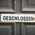 zu sehen ist eine typische deutsche alte geschlossene Rathaustür. Auf einem weißen Schild an der Tür steht mit dicken schwarzen Buchstaben „GESCHLOSSEN“.