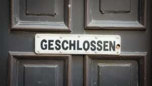 zu sehen ist eine typische deutsche alte geschlossene Rathaustür. Auf einem weißen Schild an der Tür steht mit dicken schwarzen Buchstaben „GESCHLOSSEN“.