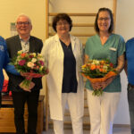 Fünf Personen stehen in einem Behandlungsraum der Klinik nebeneinander, darunter Vertreter des RSV Ilfeld e.V., die Chefärztin der Lungenklinik und die Übungsleiterin. Zwei Frauen halten Blumensträuße in den Händen.