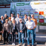 Gruppenfoto der Organisatoren und Sponsoren des Harztorlaufs 2025 vor dem Banner mit den Logos der Partner am Mehrzweck-Gebäude in Harztor.