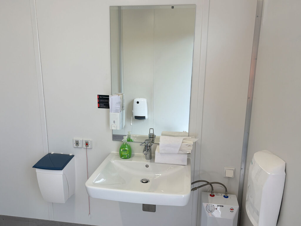 Waschbereich der neuen barrierefreien Toilettenanlage mit Spiegel, Seifenspender und Waschbecken am Bahnhof Niedersachswerfen Ost.