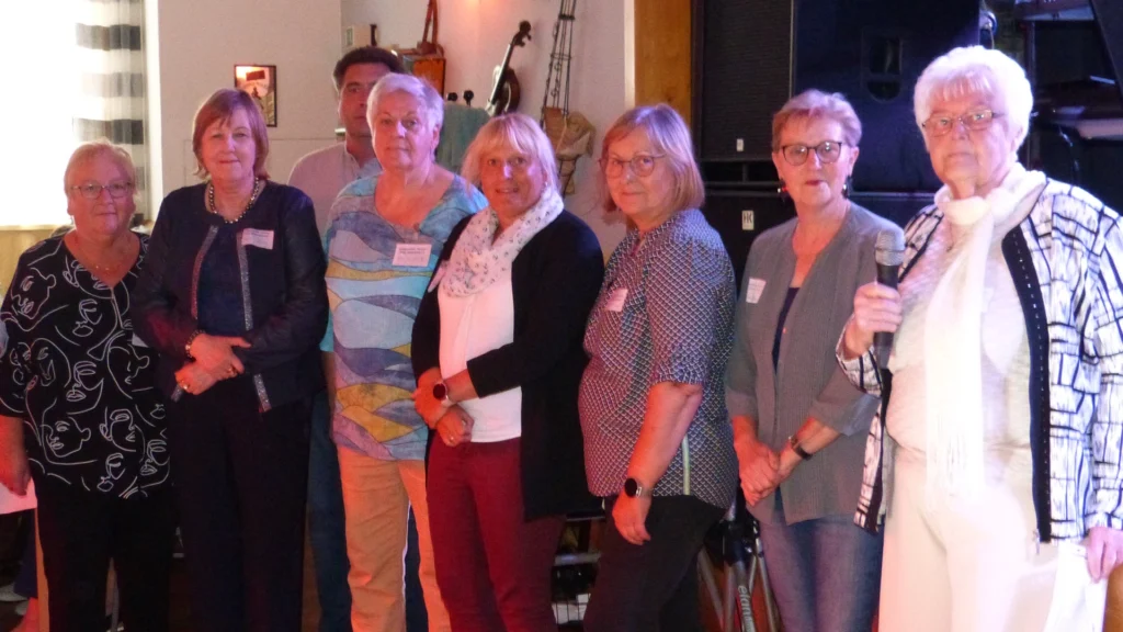 Seniorenfest Harztor: Gruppenfoto auf der Bühne – mehrere Frauen mit Namensschildern, eine Frau mit Mikrofon; warmes Bühnenlicht.