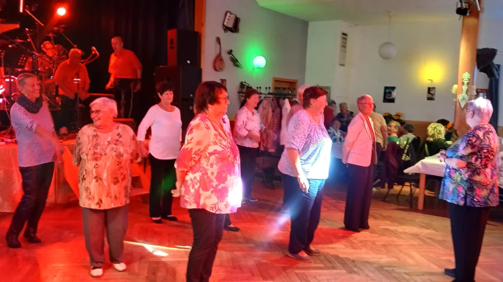 Seniorenfest Harztor: gemeinsamer Tanz vor der Bühne; Seniorinnen in Reihe, Live-Musik im Hintergrund, bunte Saalbeleuchtung.