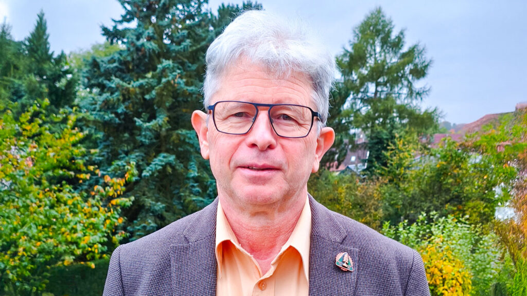 Vizepräsident des Harzklub e.V. Dirk Erfurt steht im Freien vor herbstlicher Naturkulisse und blickt in die Kamera.