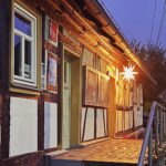 Tourist-Information in einem historischen Fachwerkhaus in der Dämmerung. Über dem Eingang leuchtet ein heller Herrnhuter Stern, der den Eingang und die Umgebung in warmes Licht taucht. Der Himmel ist blauviolett, die Straße davor ruhig und menschenleer – stimmungsvolle Aufnahme in der Vorweihnachtszeit.