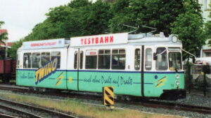 Die Testbahn „Twino“ auf einem Gleisabschnitt in Nordhausen. Die grün-weiße Versuchsstadtbahn trägt den Schriftzug „Twino – auch ohne Draht auf Draht“ und diente in den 1990er-Jahren zur Erprobung des neu entwickelten Hybridantriebs für den späteren Combino Duo.