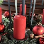 Ein weihnachtliches Gesteck mit Tannenzweigen und roten Kerzen.