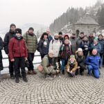 Zufriedene Teilnehmer der Talsperrenwanderung posieren auf der Staumauer, Winterbild.