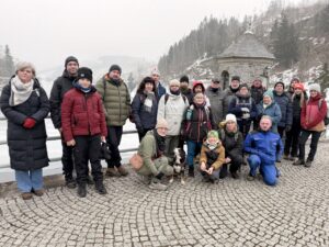 Zufriedene Teilnehmer der Talsperrenwanderung posieren auf der Staumauer, Winterbild.