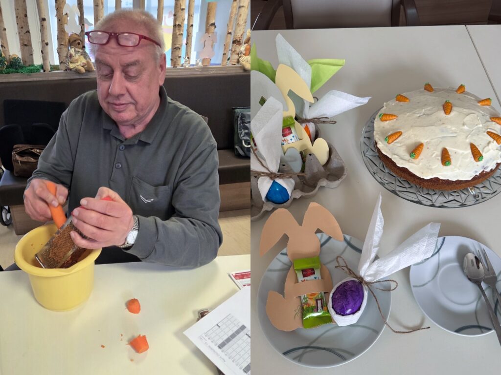 Ein Senior in grünem Poloshirt sitzt am Tisch und reibt konzentriert eine Möhre über einer gelben Kunststoffschüssel. Seine rote Lesebrille hat er in die Stirn geschoben. Vor ihm auf dem Tisch liegen bereits geschälte Möhrenstücke. Im Hintergrund sind die frühlingshafte Dekoration der Tagespflege mit Birkenstämmen, kleinen Osterhasen-Figuren und Fensterbildern zu erkennen – eine ruhige, häusliche Atmosphäre.
Aufsicht auf einen fertig gebackenen Karottenkuchen, der auf einer silbernen Tortenplatte mit Kristallmuster angerichtet ist. Der Kuchen ist großzügig mit heller Zuckerguss-Creme bestrichen und mit kleinen Marzipan-Möhrchen verziert. Links im Bild stehen österliche Tischdekorationen: ein Eierkarton mit bunt bemalten Eiern, Papier-Osterhasen in Pastellfarben, grüne Servietten und eine kleine Schokoladen-Gabe. Rechts wartet ein Dessertteller mit Kuchengabel und Löffel auf den ersten Anschnitt – ein einladender Oster-Kaffeetisch.