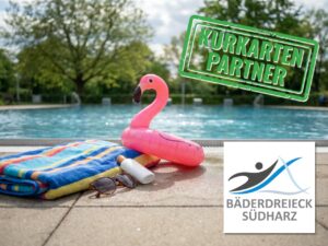 Nahaufnahme vom Beckenrand eines Freibades an einem sonnigen Frühsommertag. Auf den warmen, leicht feuchten Fliesen liegen ein buntes Streifenhandtuch, eine Sonnenbrille und eine kleine Flasche Sonnencreme. Halb auf dem Handtuch ruht ein rosafarbenes Aufblas-Flamingo. Im Hintergrund das blaue, leicht gekräuselte Wasser des Beckens. Logos vom Bäderdreieck und Kurkarten-Partner.
