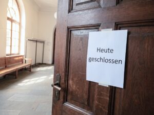 Geschlossene B&uuml;rot&uuml;r einer Verwaltung mit einem gedruckten Schild &bdquo;Heute geschlossen". Ruhiger Flur, Morgenlicht f&auml;llt durch ein Seitenfenster.