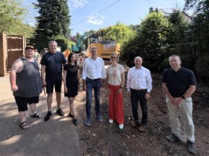 Gruppenfoto an der Baustelle in der Neuen Marktstraße: sieben Personen, in der Mitte Bürgermeister Stephan Klante und Finanzministerin Katja Wolf. Hinter der Gruppe stehen zwei Bagger.
