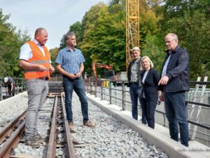 Besichtigung auf dem sanierten HSB-Viadukt bei Ilfeld: Personen stehen an den Gleisen, im Hintergrund Kran und Wald. Foto: HSB/Dirk Bahnsen