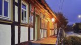 Tourist-Information in einem historischen Fachwerkhaus in der Dämmerung. Über dem Eingang leuchtet ein heller Herrnhuter Stern, der den Eingang und die Umgebung in warmes Licht taucht. Der Himmel ist blauviolett, die Straße davor ruhig und menschenleer – stimmungsvolle Aufnahme in der Vorweihnachtszeit.