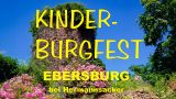 Plakat für das Kinder-Burgfest: Vor tiefblauem Himmel ragt die überwachsene, runde Turmruine der Ebersburg empor; im Vordergrund blühen leuchtend pinke Rosensträucher. Gelbe Hand­schrift-Schriftzüge darüber: „KINDER-BURGFEST – EBERSBURG bei Hermannssacker“.