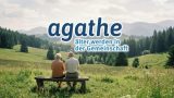 Ein älteres Paar sitzt von hinten auf einer Holzbank und blickt über eine grüne Sommerwiese auf bewaldete Berge. Über dem Bild steht der Schriftzug „agathe – älter werden in der Gemeinschaft".