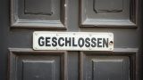 zu sehen ist eine typische deutsche alte geschlossene Rathaustür. Auf einem weißen Schild an der Tür steht mit dicken schwarzen Buchstaben „GESCHLOSSEN“.