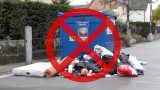 Symbolbild: Verbotene Ablage neben einem vollen Textilsammelcontainer – Matratze, Teppich, Zelt, defekte/verschmutzte Kleidung am Boden; roter Verbotskreis und rotes X markieren „Abladen verboten“. KI