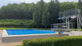 Ein Freibad am Waldrand, menschenleer, es regnet stark